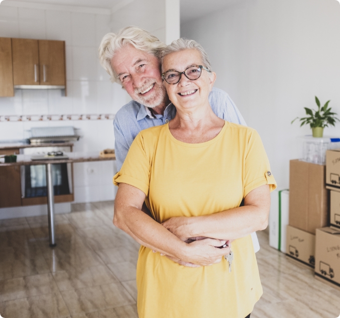 portrait-smiling-senior-couple-with-white-hair-embraced-during-relocation-happy-new-beginning-like-retired-with-moving-boxes-floor